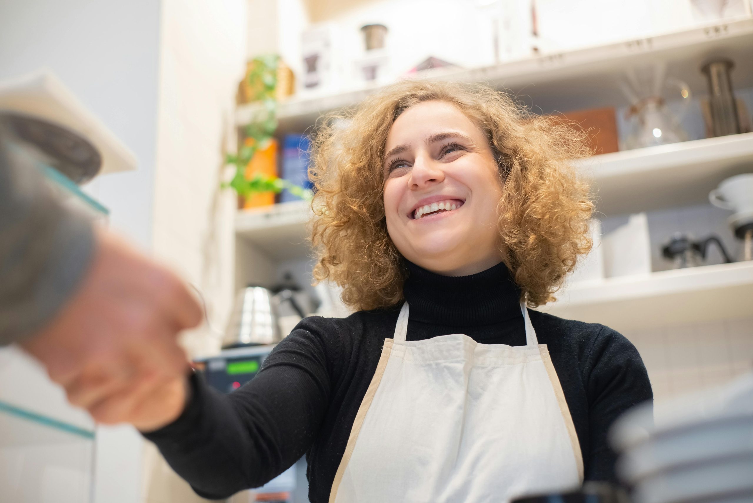 Standard Restaurant Supply Mesa AZ - Service with a Smile Smiling female employee in an apron shaking hands with a customer in a welcoming kitchen supply store, reflecting excellent customer service at Standard Restaurant Supply in Mesa, Arizona.